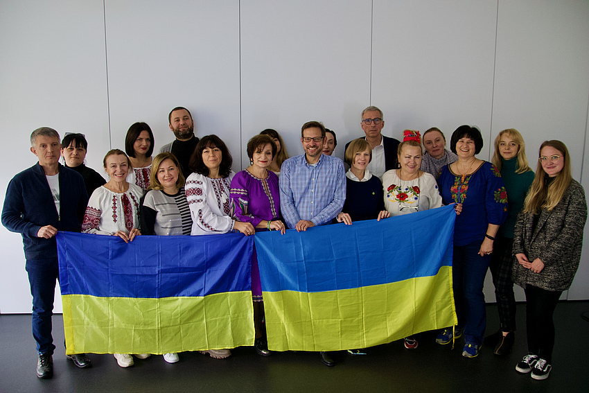 Eine Gruppe ukrainischer Besucher posiert mit ukrainischen Flaggen.